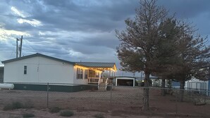 En enplansbyggnad med en inhägnad trädgård, en överbyggd veranda och ett garage.