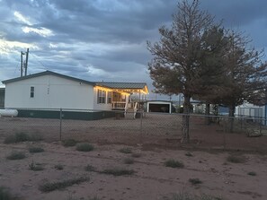 A single-story building with a fenced yard, a covered porch, and a garage.