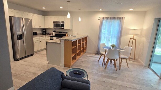 A modern kitchen with built-in appliances, a dining area with a table and chairs, and a living area with a sofa. - Luxurey-bedroom house in charming Homosassa with AC (Homosassa)