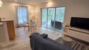 A modern living room with a sofa, a dining area with chairs, a TV, and a large window. - Luxurey-bedroom house in charming Homosassa with AC (Homosassa)