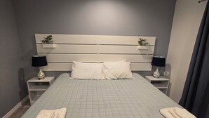 A bedroom with a large bed, two bedside tables with lamps, a headboard with built-in shelves, and a ceiling light. - Luxurey-bedroom house in charming Homosassa with AC (Homosassa)