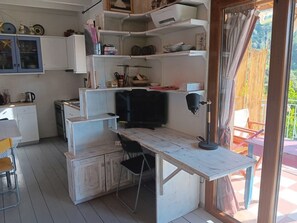 A compact kitchen with a dining area, a television, and a view of the outdoors. - "House of Thalia" A Mediterranean home with soul and history (Manolates)