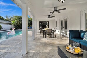 A covered outdoor patio with a pool, dining area, and seating. - Waterfront Pool Home • Hot Tub • Private Golf Field (Tampa)