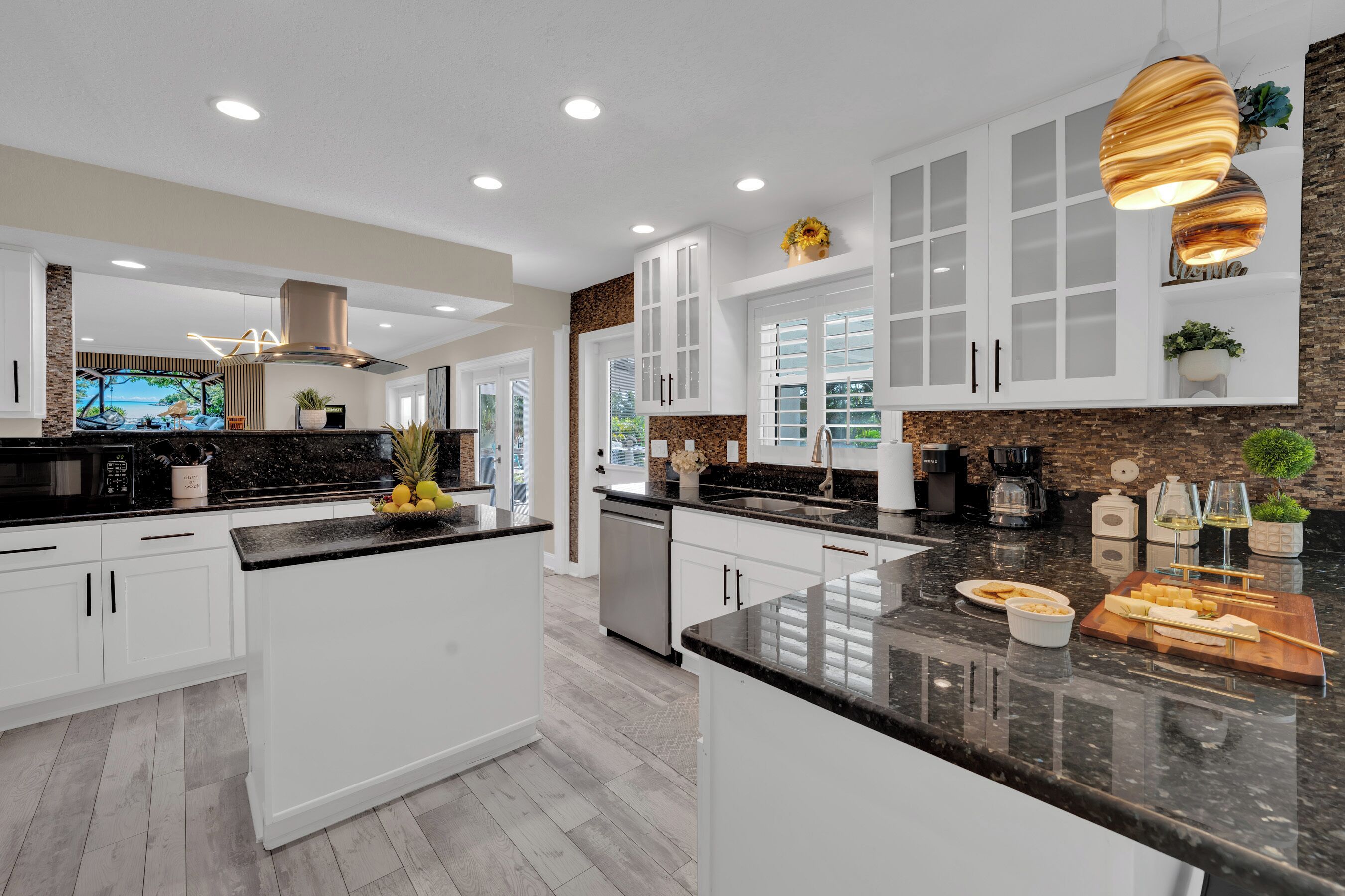 A modern kitchen with white cabinetry, granite countertops, and a central island with a fruit bowl.
