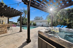 A backyard with a hot tub, a pool, and a pergola with string lights. - Waterfront Pool Home • Hot Tub • Private Golf Field (Tampa)