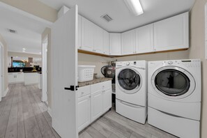 A modern laundry room with white cabinets and two front-loading washing machines. - Waterfront Pool Home • Hot Tub • Private Golf Field (Tampa)