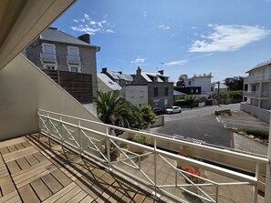 A residential street with houses, a clear sky, and a balcony with a railing. - Le Primauguet ,Terrace ,50m from the beach (Saint-Cast-le-Guildo)
