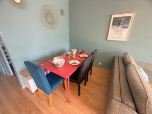 A dining area with a red table, blue chair, and a grey sofa. - Le Primauguet ,Terrace ,50m from the beach (Saint-Cast-le-Guildo)