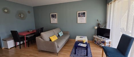 Ett vardagsrum med en soffa, ett soffbord, ett TV-bord och en matplats.