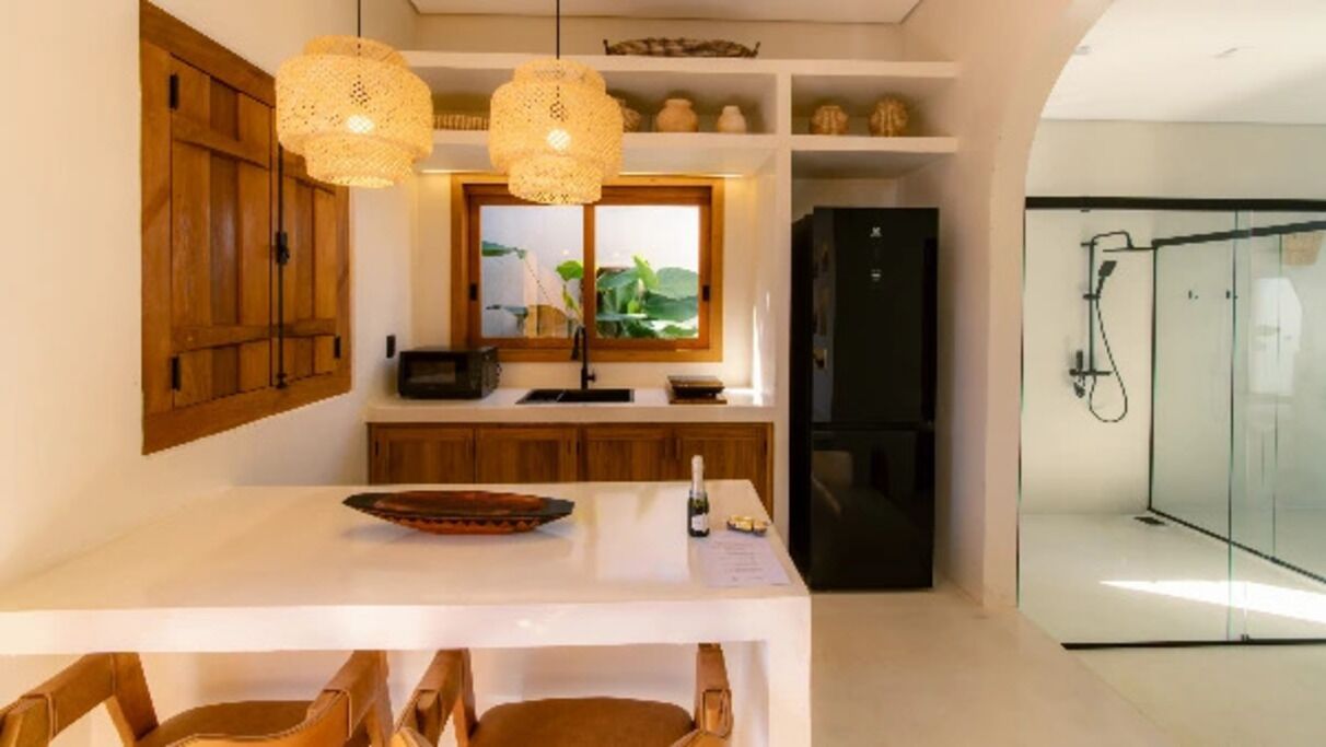 A modern kitchen with wooden cabinets, a white countertop, and two hanging light fixtures.