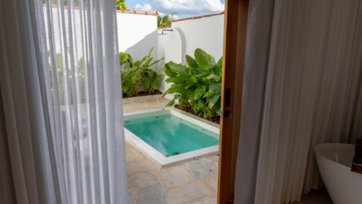 A view through a doorway into a swimming pool area with a tiled floor and plants.