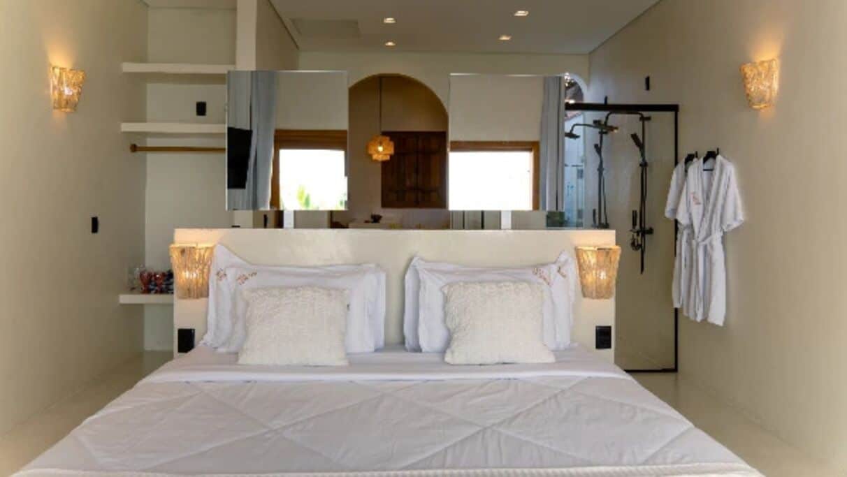 Ein Hotelzimmer mit einem großen Bett, einem Badezimmer mit Dusche und einem Spiegel über dem Bett.