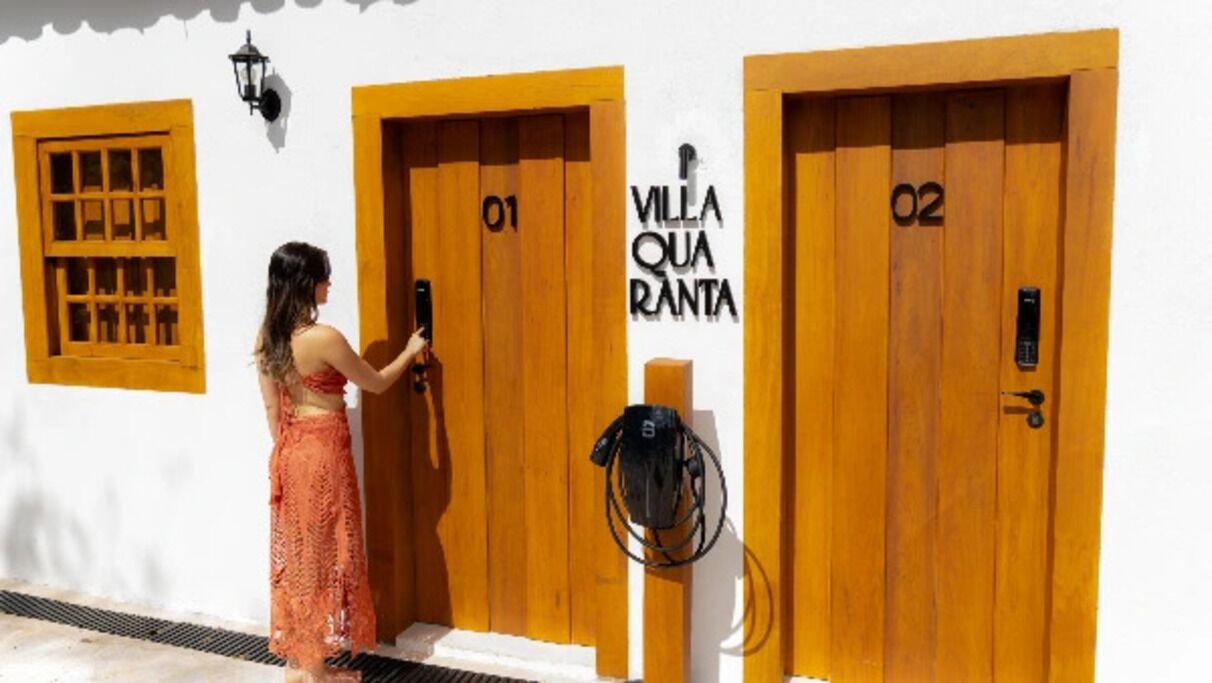 Una mujer en la entrada de un hotel, con puertas identificadas como '01' y '02', y un cartel que dice 'VILLA QUARANTA'.