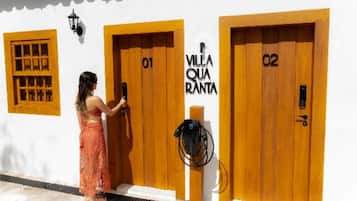 Una mujer en la entrada de un hotel, con puertas identificadas como '01' y '02', y un cartel que dice 'VILLA QUARANTA'.