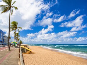 Ein Strand mit Palmen, sandigem Ufer und blauem Himmel.
