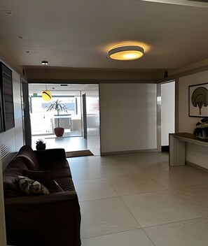 A modern living room with a sofa, a coffee table, and a dining area with a table and chairs. - Amaralina 418 (Salvador)
