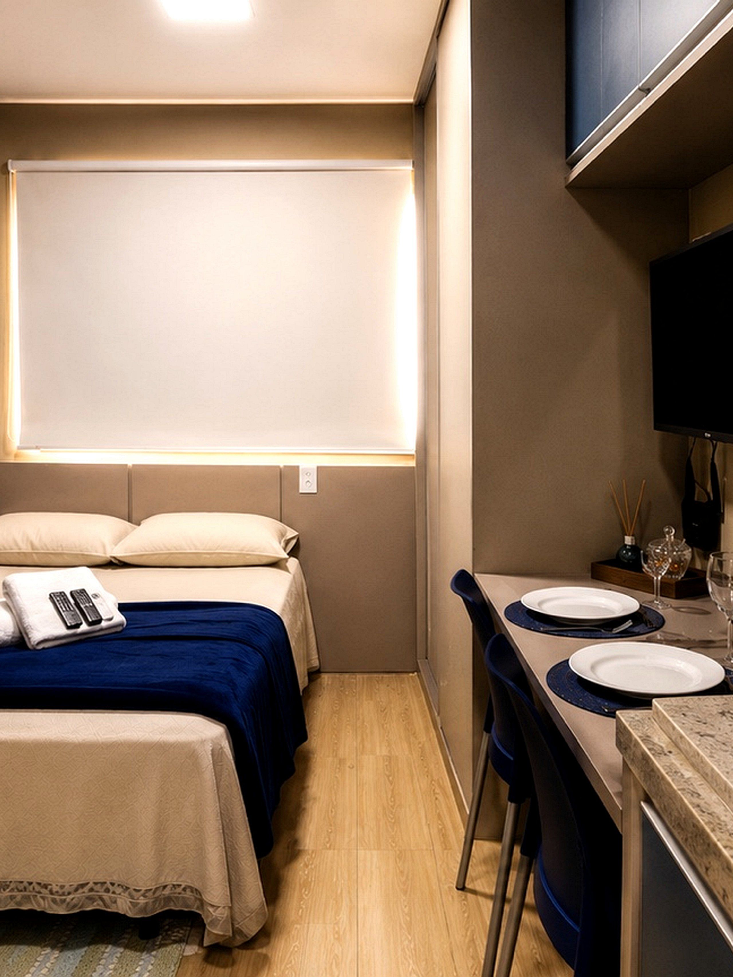 Ein kleines Hotelzimmer mit einem Bett, einem Nachttisch und einer kleinen Küchenzeile.