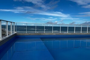 A pool with a clear view of the ocean and distant mountains. - Amaralina 418 (Salvador)