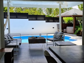 A covered outdoor area with a pool, seating, and a pergola structure. - Villa Tartaruga - piscine privée, proche plage et centre ville (Sainte-Anne)