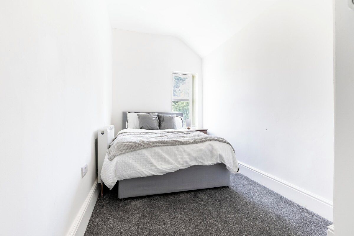 A bedroom with a bed, a window, and a radiator.