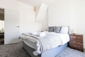 Een slaapkamer met een bed, nachtkastje en een deur.