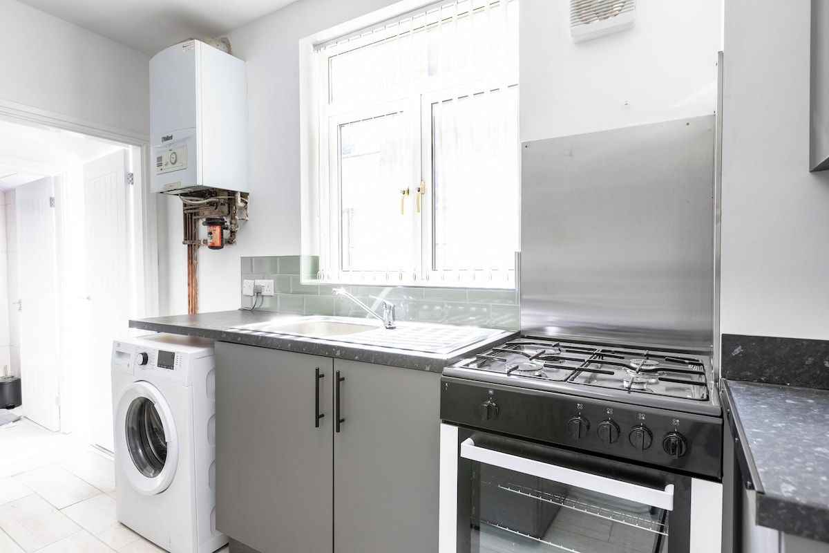 A compact kitchen with a washing machine, a gas stove, and an oven.
