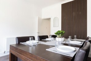 A dining area with a long table set for four, surrounded by chairs, with a potted plant on the table. - 46 Gladstone Street Walsall (Walsall)
