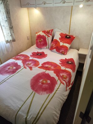 Una cama con una colcha estampada con motivos florales y almohadas a juego.
