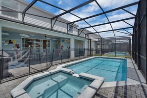 A swimming pool with a glass enclosure, a covered patio area, and a mural with cartoon characters. - Enchanted Escape Villa (Davenport)