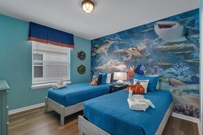 Una habitación con dos camas, un mural de vida marina submarina y una ventana con persianas.