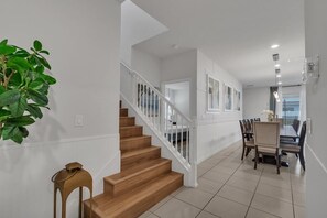 A staircase leading to a dining area with a table and chairs. - Enchanted Escape Villa (Davenport)