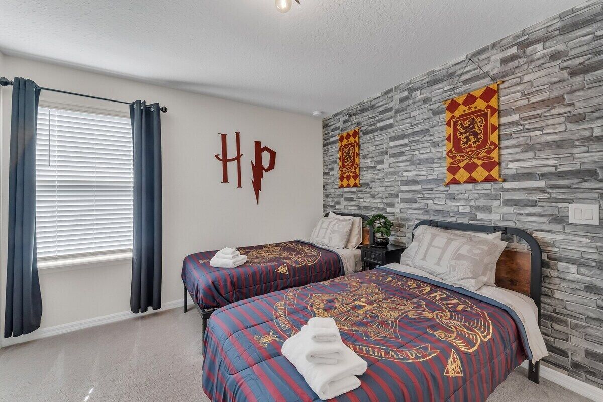 A hotel room with two beds, a stone wall, and a window with curtains.
