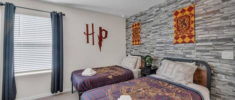 A hotel room with two beds, a stone wall, and a window with curtains.