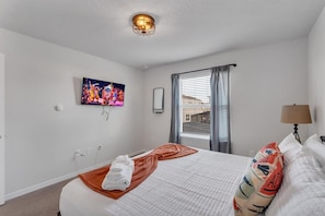 Ein Hotelzimmer mit einem Bett, einem Fernseher, einem Fenster mit Vorhängen und einer Lampe.