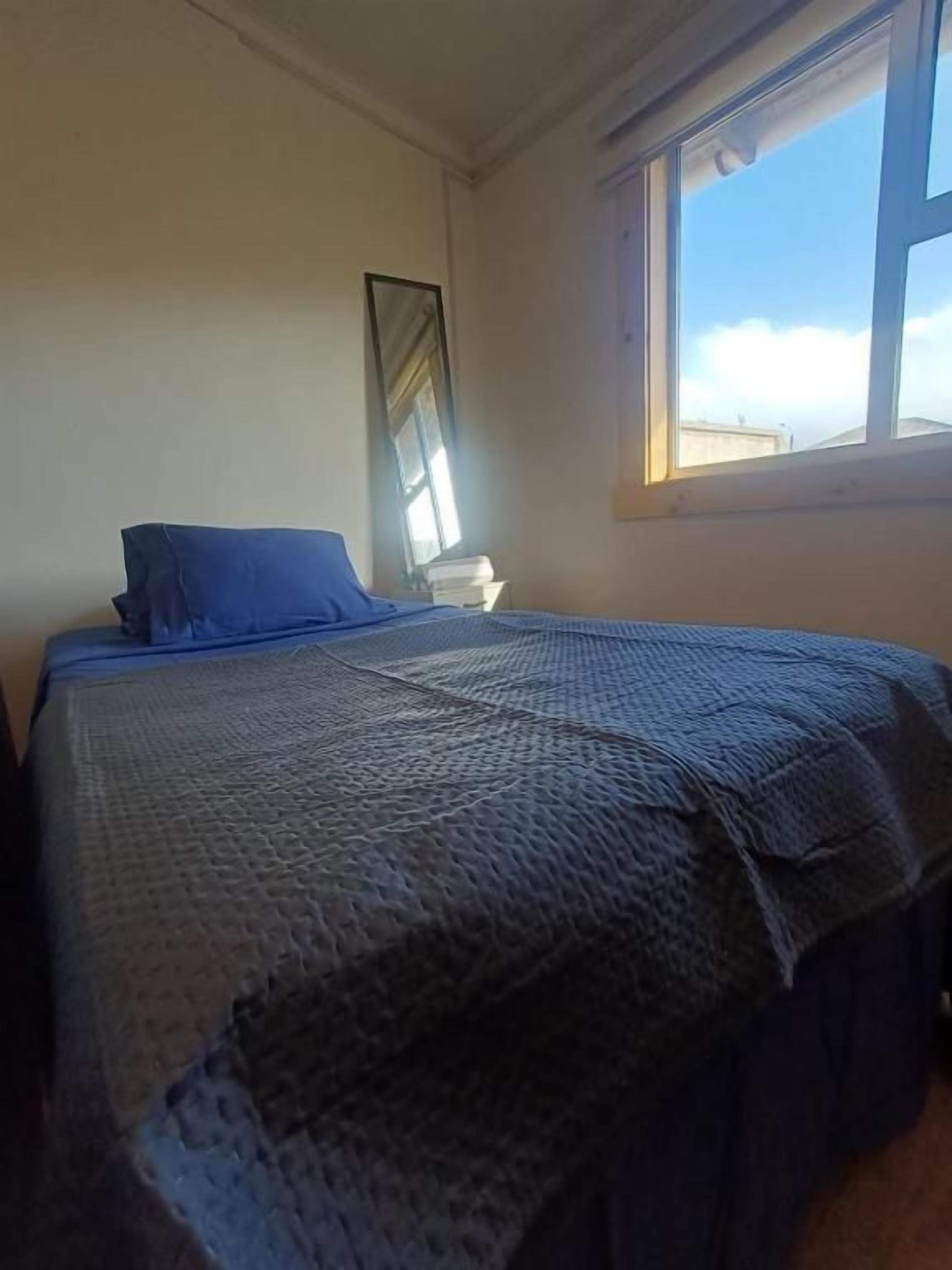 Una stanza con un letto, una finestra e uno specchio a parete.