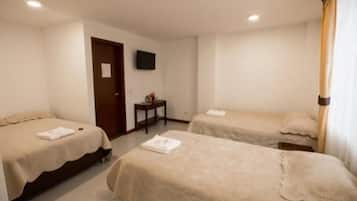A hotel room with two single beds, a small table, a television, and a door.
