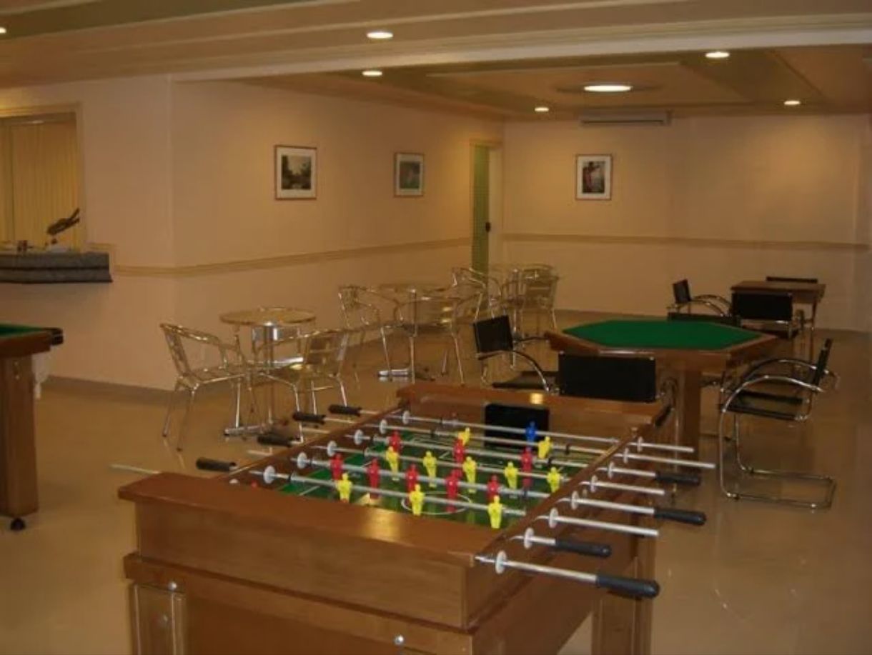 Um quarto com mesa de pebolim, cadeiras e mesa de bilhar.