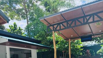 A swimming pool with a wooden deck and a covered seating area.