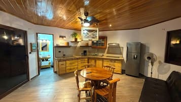 Une cuisine moderne avec des meubles en bois, une table à manger et un ventilateur de plafond.