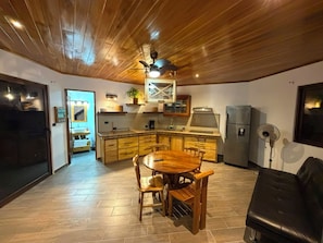 A modern kitchen with wooden cabinets, a dining table, and a ceiling fan.