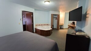 Una camera d'albergo con un letto, una vasca da bagno, una scrivania e un telefono, e una televisione.