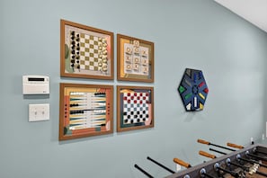 Una pared con cuatro juegos de mesa enmarcados y una mesa de fútbol de mesa.