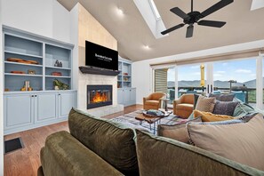 Uma sala de estar moderna com lareira, assentos confortáveis e uma grande janela com vista panorâmica.