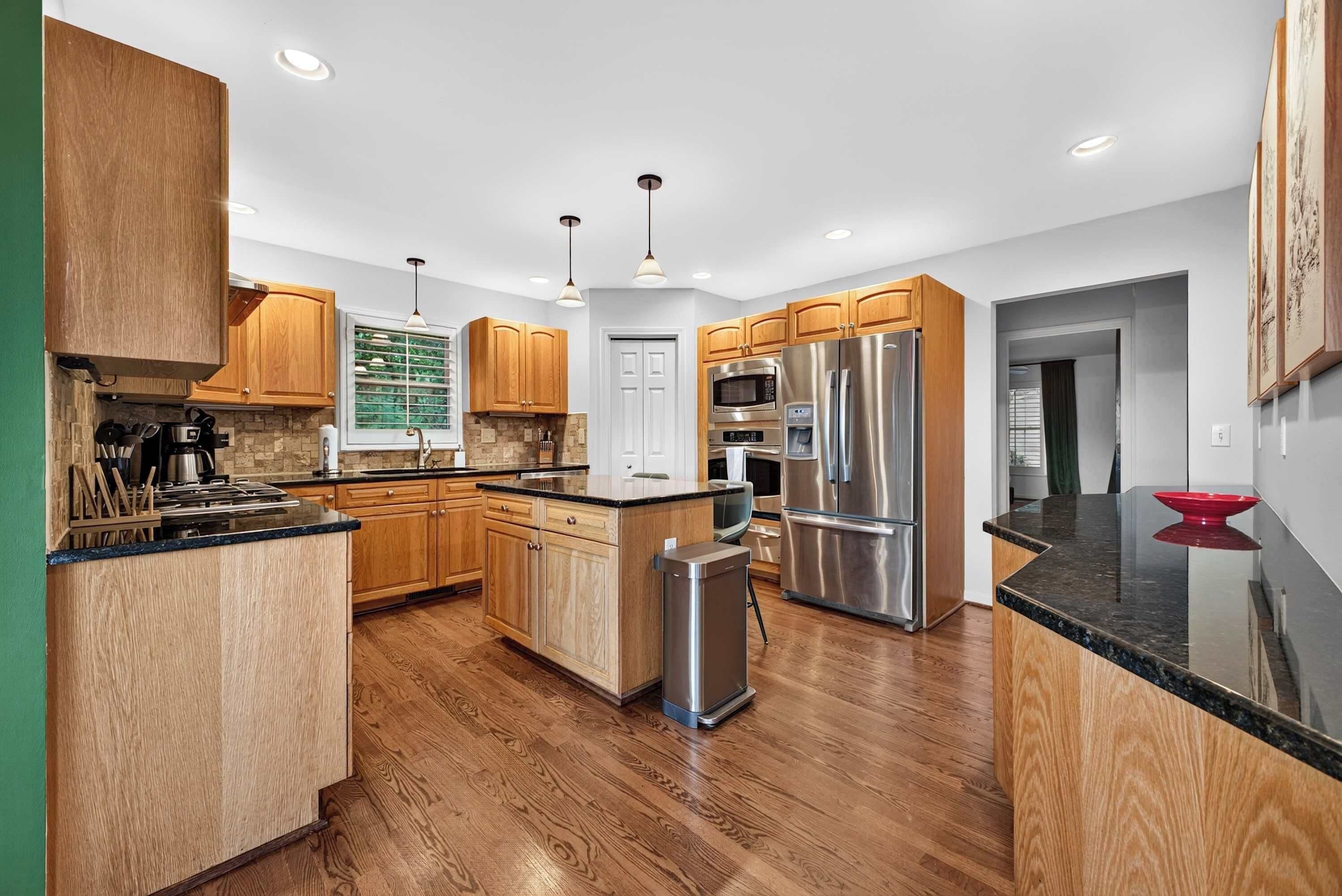 A modern kitchen with wooden cabinets, stainless steel appliances, and a central island.