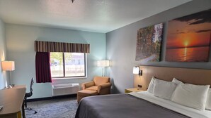 Una camera d'albergo con un letto, una scrivania, una sedia, una finestra con tende e decorazioni alle pareti.
