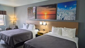 Camera d'albergo con due letti, un comodino, una lampada e tre quadri appesi al muro.