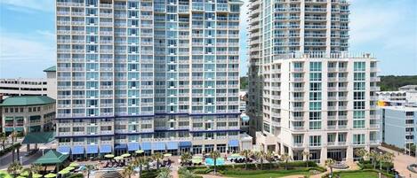 A high-rise hotel with multiple balconies, a swimming pool, and a landscaped courtyard.