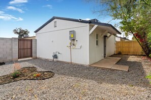 A single-story building with a flat roof, a small porch, and a gravel driveway. - 1BR Modern Cowboy Casita in Central Phoenix! (Phoenix)