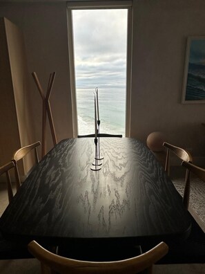 Ett matbord med utsikt över havet genom ett fönster.