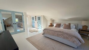 Ein Schlafzimmer mit einem großen Bett, einem Schreibtisch und einem Kleiderschrank mit Spiegelüren.